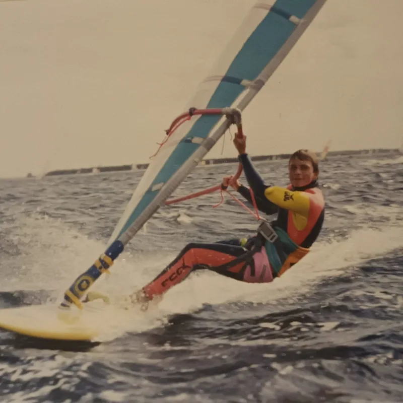 Windsurfer hangt in het trapeze en planeert over het water